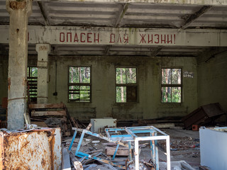 Fototapeta na wymiar Interior of an abandoned military building in Chernobyl-2 city in Chernobyl Exclusion Zone, Ukraine (russian inscription: Danger for life!)
