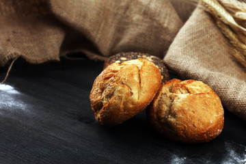 Assortment of baked bread and bread rolls on black table background