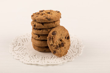 Chocolate chip cookies stacked in beautiful white lace, white background. close up
