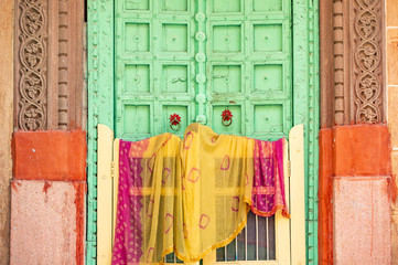 Stunning view of a traditional Indian home with a green wooden door and colorful traditional Indian...