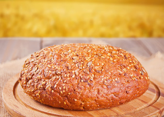 freshly baked rye bread with cereal and seeds and wheat stems on wooden kitchen table. Top view. Copy space.