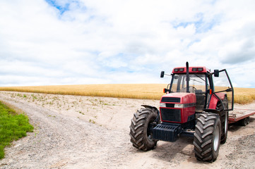 Fototapeta premium Red​ tractor with malt farm​ and cloud sky
