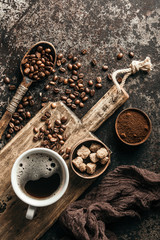 Coffee on wooden board with coffee beans on dark textured background. Top view with copy space....
