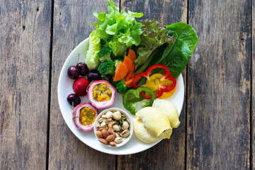 Fruit and Vegetable salad on a white plate on a wooden table