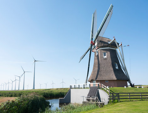 old windmill and modern wind turbines under bluw sky