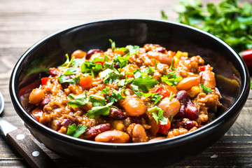 Chili con carne from meat and vegetables on wooden table top view.