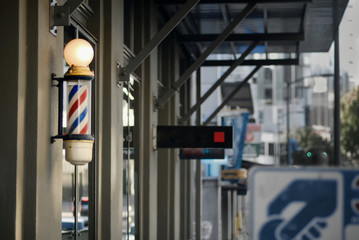 A barbershop pole along the facade of a retail building.
