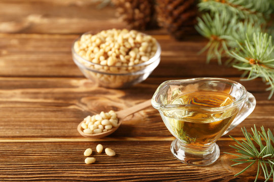 Cedar products: cedar oil, pine nuts, cones, brunches on a wooden broun background.