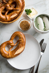 Münchener Weißwurst in Terrine mit bayrischer süßen Senf, Brezel und Butter auf Marmor Tisch