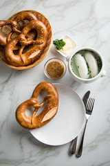 Münchener Weißwurst in Terrine mit bayrischer süßen Senf, Brezel und Butter auf Marmor Tisch