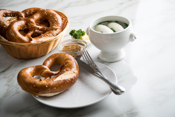 Münchener Weißwurst in Terrine mit bayrischer süßen Senf, Brezel und Butter auf Marmor Tisch