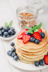 Classic american pancakes with fresh berry on white wood background. Summer homemade breakfast.