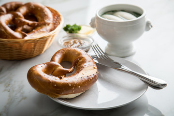 Münchener Weißwurst in Terrine mit bayrischer süßen Senf, Brezel und Butter auf Marmor Tisch