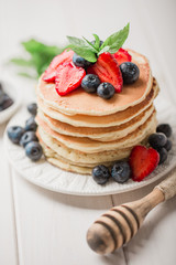 Classic american pancakes with fresh berry on white wood background. Summer homemade breakfast.