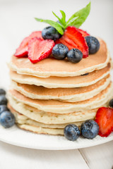 Classic american pancakes with fresh berry on white wood background. Summer homemade breakfast.