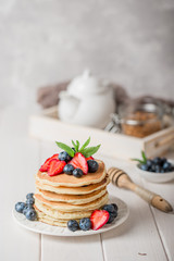 Classic american pancakes with fresh berry on white wood background. Summer homemade breakfast.