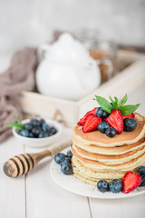 Classic american pancakes with fresh berry on white wood background. Summer homemade breakfast.