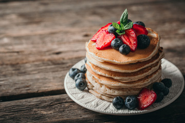 American pancakes with fresh berry on wood background. Summer homemade breakfast.