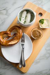 Münchener Weißwurst in Terrine mit bayrischer süßen Senf, Brezel und Butter auf Holz Brett