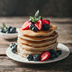 American pancakes with fresh berry on wood background. Summer homemade breakfast.