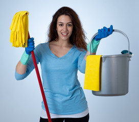 Young attractive woman holding cleaning tools and products in bucket isolated on blue background