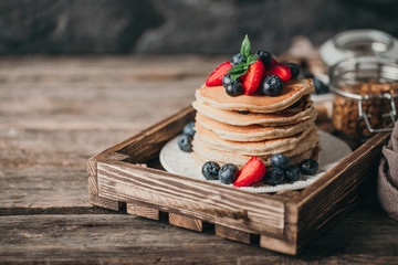 American pancakes with fresh berry on wood background. Summer homemade breakfast.