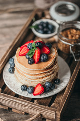 American pancakes with fresh berry on wood background. Summer homemade breakfast.
