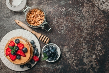 American pancakes with fresh berry and granola on metal background. Summer homemade breakfast.