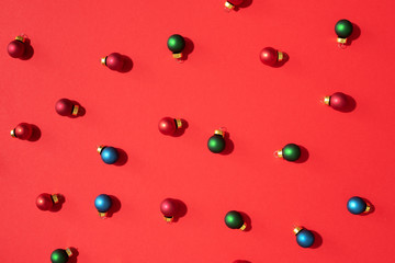 Christmas pattern made of colorful christmas baubles on red background. Flat lay, top view. New year concept