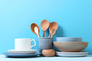 A set of dishes and kitchen utensils on a colored background.