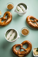 Münchener Weißwurst in Terrine mit bayrischer süßen Senf, Brezel und Butter auf Pastell grünen...
