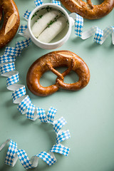 Münchener Weißwurst in Terrine und Brezel mit Oktoberfest Luftschlangen auf Pastell grünen Hintergrund