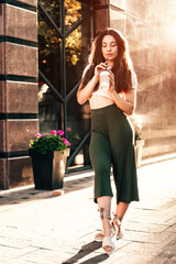 Fototapeta na wymiar Smiling woman drink coffee walking on the city in summer day.