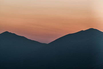 background photograph of a sunset in the mountains, on the Gran Sasso in Italy, with beautiful orange yellow green brown colors - image
