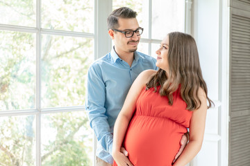 expectant parents waiting for their first child. a pregnant woman in a red dress with her husband. young parent