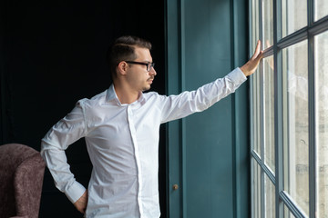 successful man stands at the window of his own house