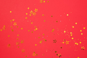 Golden star sparkles on red background. Christmas and New year concept. Festive backdrop with copy space