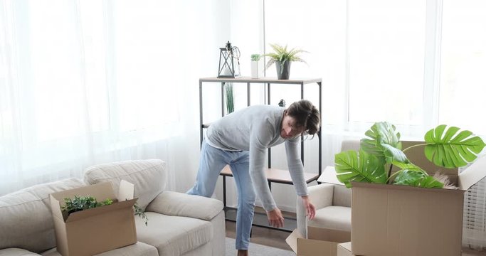 Man moving into new house decorating plants and lamp on shelf