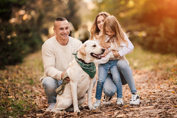 Fototapeta premium Happy family is having fun with dog labrador outdoors.