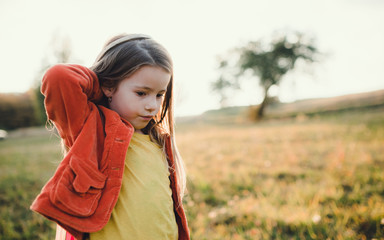 A small girl walking in autumn nature at sunset, playing.