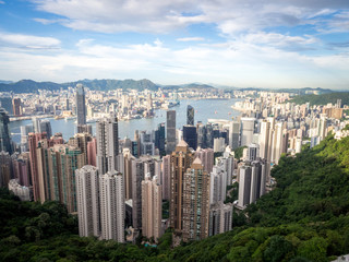 Fototapeta na wymiar Hong Kong Skyline from the Famous Victoria Point at Daytime. Green forest and river surrounded by towering sky scrapers which is densly populated