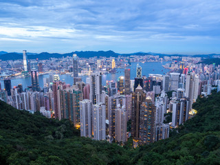 Hong Kong Skyline at Sunset from the Famous Victoria Point at Daytime. Green forest and river surrounded by towering sky scrapers which is densly populated