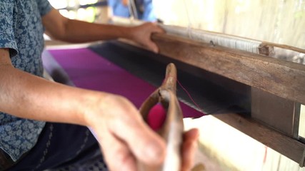 Old women are using the machine - Household Loom weaving - for homemade silk or textile production of Thailand 