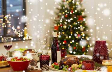 christmas dinner and eating concept - food and drinks on table at home over snow