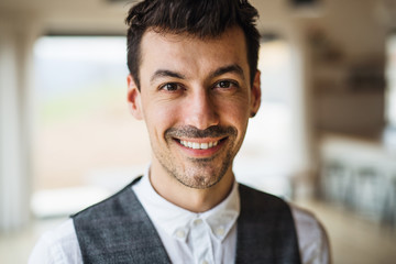 Fototapeta premium Portrait of young man standing indoors at home, looking at camera.