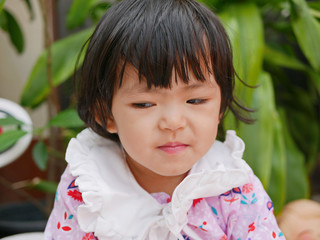 Portrait of a little Asian baby girl, 24 months old, with a cunning look / smile