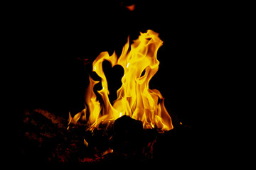 bonfire brightly on a black background at night in a travelers camp. - Horizontal image