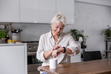 Mature adult woman looking at smartwatch smiling