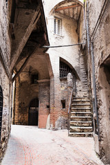 Photograph of small streets in the center of Perugia, with medieval houses, bricks and gates.