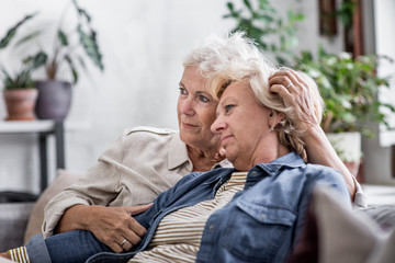Mature lesbian couple at home on sofa